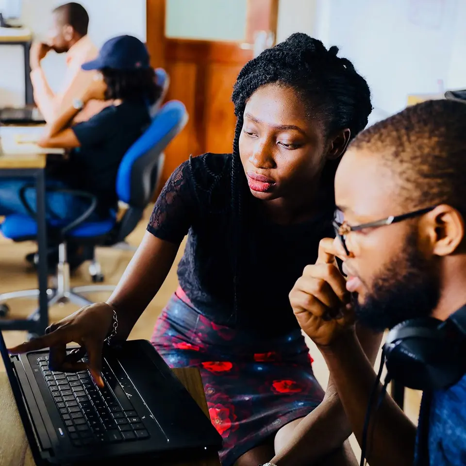 Two colleagues working through a problem together at a laptop