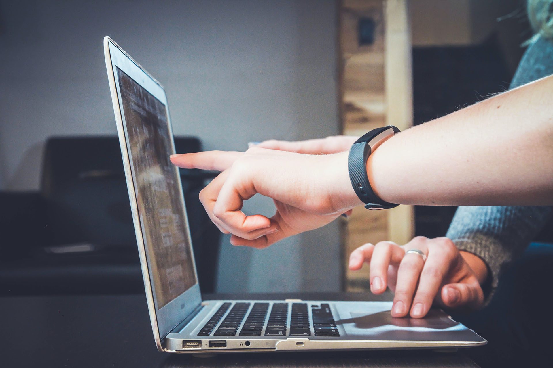 Hands pointing at a laptop on a desk